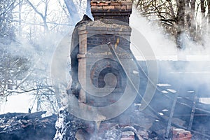 Brick oven at the site of the ruins of a burnt house, thick smoke after a fire