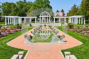 Brick pathway leading to pools of water and white pergola with trellises at Lakeside Park