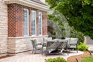 A brick patio in front of a luxury stone home.