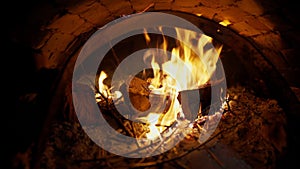 A brick pizza oven with fire and flame. Firewood burning in the wood-fired oven with open door. A traditional oven for