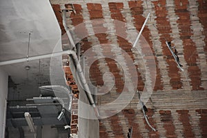 Brick room walls and ceiling view of a being demolished building with electricity, water and ventilation installations