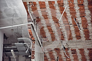 Brick room walls and ceiling view of a being demolished building with electricity, water and ventilation installations