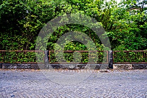 Brick sidewalk with metal fence and trees in the backgroud in Germany.