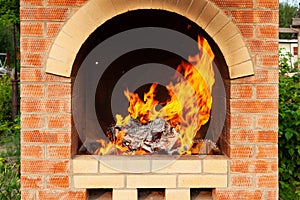 Brick stove in the yard with large flames from the fire in preparation for cooking meat in the open air