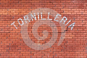 Brick wall background with Tornilleria text