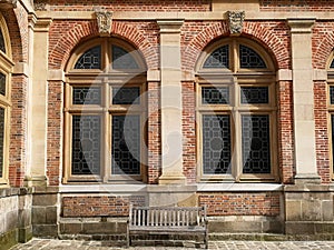 Brick wall and a bench under large windows