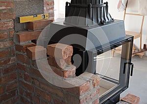 Brick wall border for a wood-burning stove or fireplace under construction in the interior fitting area