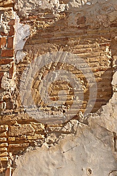 Brick wall covered with stucco deteriorating in Spain