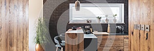 Brick wall in elegant kitchen with wooden island and styli