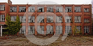 Brick wall facade with broken windows of an abandoned school