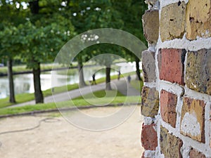 A brick wall in front of a park with trees
