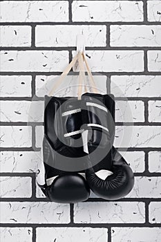 On the brick wall is a hook on which a pair of black boxing gloves hangs