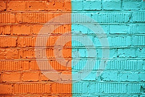 Brick wall, painted half orange and turquoise paint, with real cracks and dents
