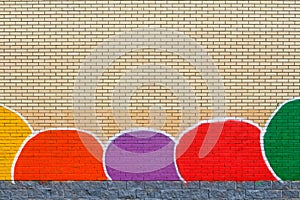 Brick wall with a painted lower part in the form of multi-colored spots and grey tiles