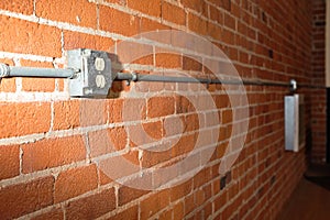 Brick wall with a power outlet and pipe