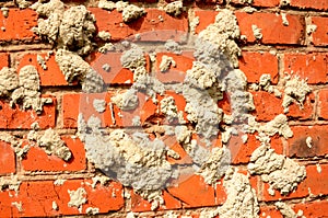 Brick wall red color, construction background. Old cracked brick is dirty with concrete, horizontal bright photo on sunny day