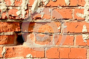 Brick wall red color with hole, construction background. Old cracked dirty brick with concrete, horizontal bright photo on a