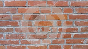 Brick wall of red-orange bricks and blocks. Lightly worn surface. Neat masonry, cement between the rows. Grunge background.