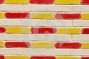 Brick wall, with red and yellow painted bricks.