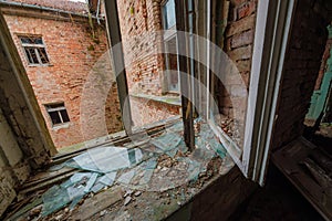 Brick wall room with broken window glasses in daylight