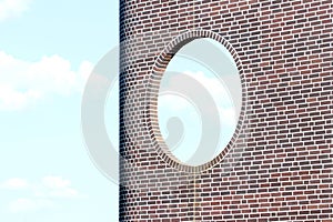 Brick wall with round window against blue sky background