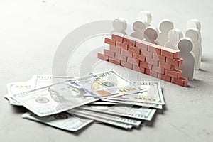 Brick wall separates money from people. The wall on the one hand many businessmen with stack of money