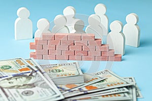 Brick wall separates money from people. The wall on the one hand many businessmen with stack of money