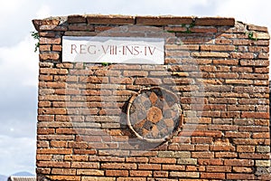 brick wall with symbol in circumference in region VIII in pompeii archeological park