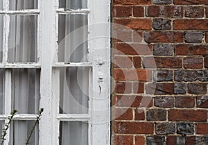 Brick wall with white window and chipped paint