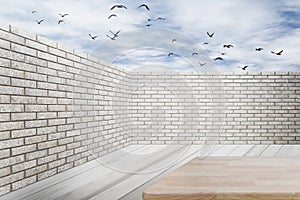 Brick wall and wooden floor with blue sky and clouds.