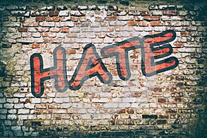 Brick wall with word hate graffiti.