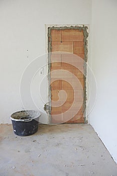 bricked up door in a living room with white walls, next to a black vat