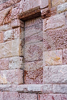 Bricked up window of an old ancient building with uneven stone wall
