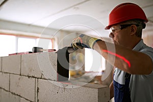 Bricklayer applies adhesive glue on autoclaved aerated concrete blocks with notched trowel. Brickwork worker contractor