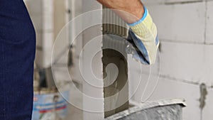 Bricklayer applies adhesive glue on autoclaved aerated concrete blocks with notched trowel. Brickwork worker contractor