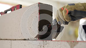 Bricklayer applies adhesive glue on autoclaved aerated concrete blocks with notched trowel. Brickwork worker contractor