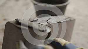 Bricklayer applies adhesive glue on autoclaved aerated concrete blocks with notched trowel and spatula. Brickwork worker