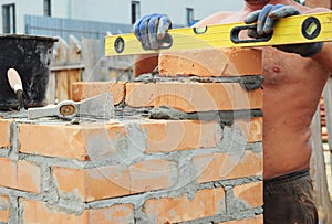 Bricklayer Bricklaying Concept. Bricklaying Tools. A bricklayer using a level to check his new house construction wall outdoor. Br