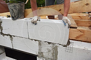 Bricklayer builder laying autoclaved aerated concrete blocks, aac for new house wall