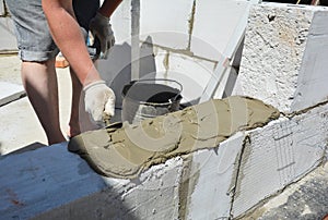 Bricklayer builder laying autoclaved aerated concrete blocks, aac.  Autoclaved aerated concrete blocks walling installation with photo