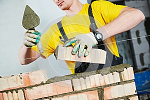 Bricklayer builder worker laying bricks wall