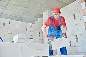 Bricklayer builder working with autoclaved aerated concrete blocks. Walling