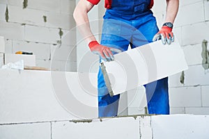 Bricklayer builder working with autoclaved aerated concrete blocks. Walling