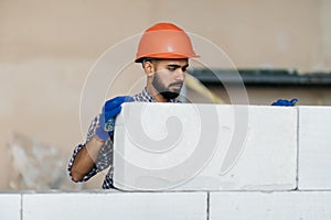 bricklayer builder working with autoclaved aerated concrete blocks. Walling, installing bricks on construction site