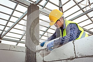 Bricklayer builder working with autoclaved aerated concrete blocks. Walling, installing bricks in construction site