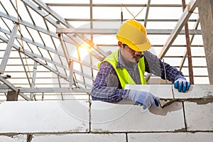 Bricklayer builder working with autoclaved aerated concrete blocks. Walling, installing bricks on construction site, Engineering