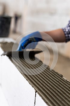 Bricklayer builder working with autoclaved aerated concrete blocks. Walling, installing bricks on construction site, Engineering