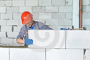 Bricklayer builder working with autoclaved aerated concrete blocks. Walling, installing bricks on construction site. Engineering