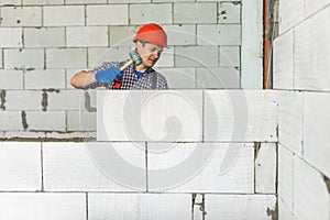 Bricklayer builder working with autoclaved aerated concrete blocks. Walling, installing bricks on construction site. Engineering