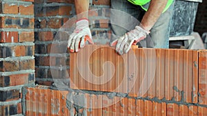 Bricklayer Building Wall with Red Bricks. Close-up of a construction worker laying red bricks with mortar, showcasing